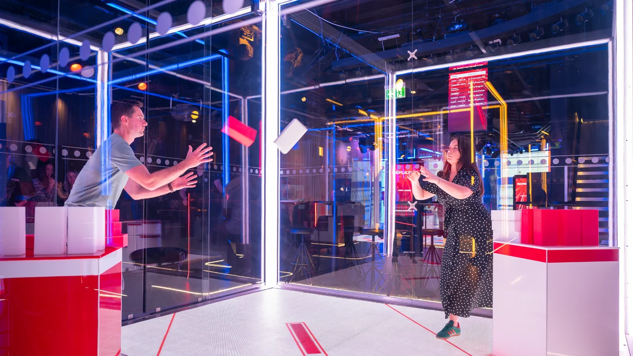 Two people in The Cube simulation throwing a foam brick to each other in a game 